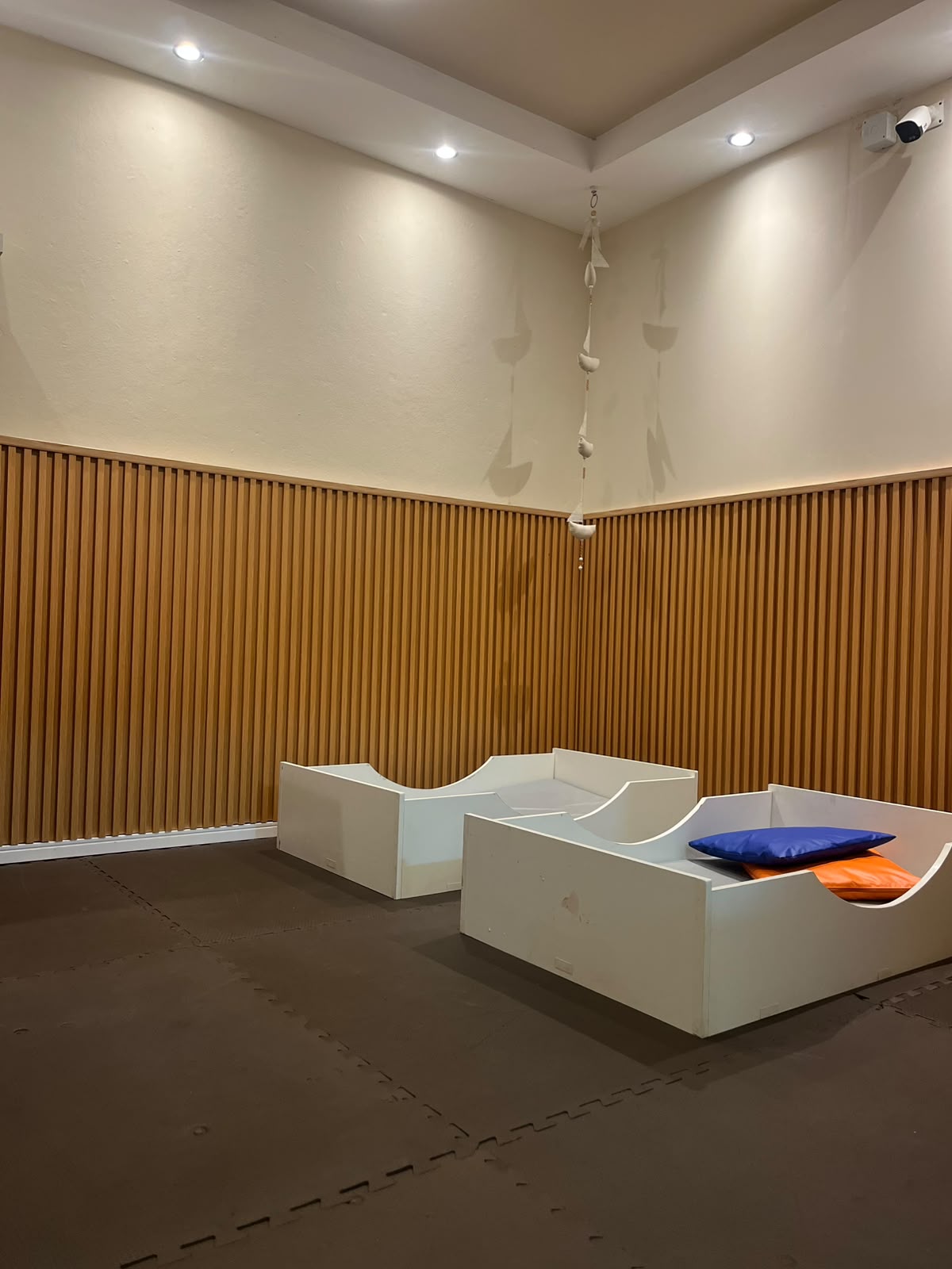 Sala do berçário com camas baixas e acabamento em madeira